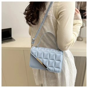 Light blue quilted crossbody bag with gold metal trim shown worn on model's shoulder