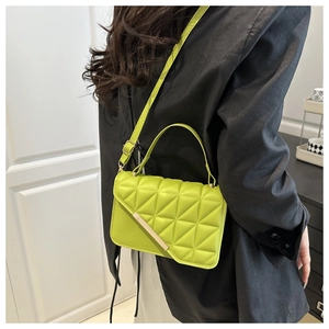 Detail of neon green quilted crossbody bag with gold metal trim and adjustable strap