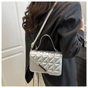 Detail of silver quilted shoulder bag with geometric stitching and gold metal trim