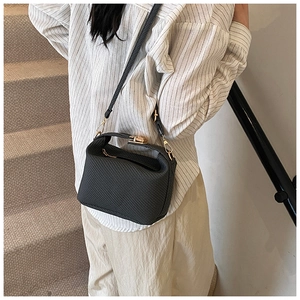 Detail of a chic black houndstooth crossbody bag with gold hardware worn by a model
