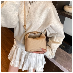 Detail of woven texture and gold metal zipper on minimalist crossbody bag with strap