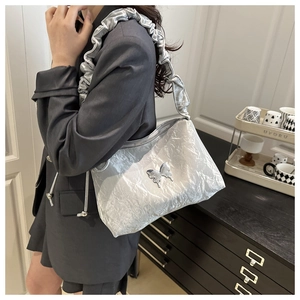 Détail du sac à bandoulière plissé argenté avec fermoir papillon et sangle à volants