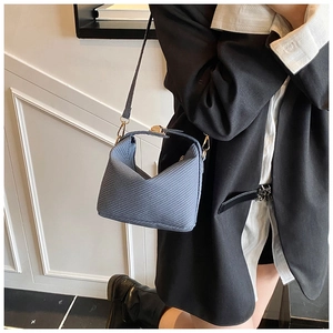 Detail of navy blue woven texture small pillow bag with gold lock and v-shaped opening