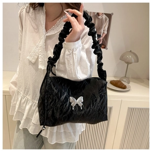 Détail du sac à bandoulière plissé noir avec breloque papillon argentée au style Y2K