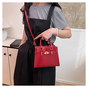 Close-up of bright red Kelly style tote bag with golden lock and adjustable strap
