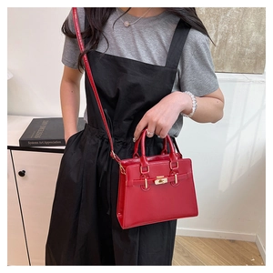 Detailed shot of a red patent leather handbag with gold metal lock on a model