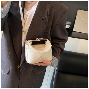 Détail du sac bandoulière crème avec texture tressée et boucles métalliques dorées chic