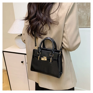 Glossy black leather Kelly handbag with gold lock shown on model with shoulder strap
