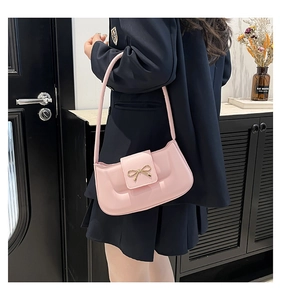 Close-up of pink quilted bag with golden bow clasp shown on a model's shoulder