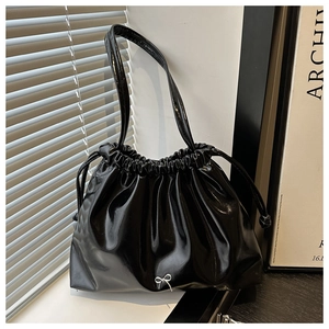 Dettaglio della borsa nera lucida a secchiello con coulisse e decorazione a fiocco argento