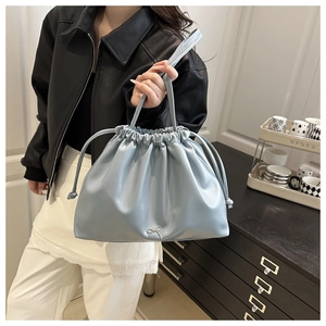 Détail du sac seau plissé bleu clair avec cordon de serrage et décoration nœud argenté