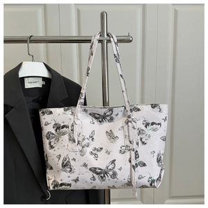 Close-up of stylish large tote bag with black butterfly patterns on white background