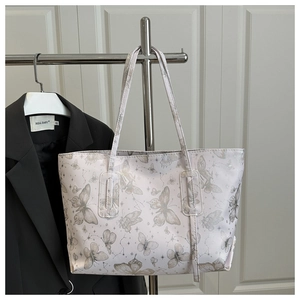 Detail of white tote bag with butterfly and star patterns hanging on a metal hanger
