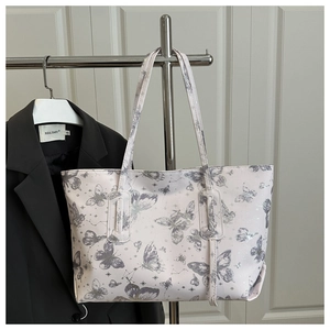 Detail of white tote bag featuring gray butterfly prints and constellation patterns