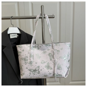 Detail of light pink tote bag with green butterfly print and celestial star patterns