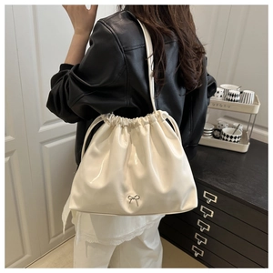 Détail du sac seau crème à cordon avec nœud argenté et cuir souple plissé élégant