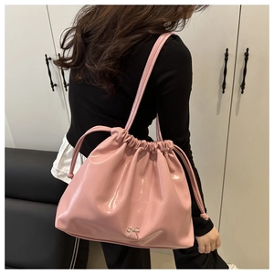 Dettaglio borsa a secchiello in pelle lucida rosa con coulisse e fiocco metallico decorativo
