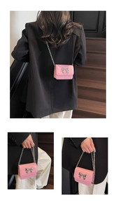 Detail view of mini pink crossbody bag with silver bow ornament and elegant metal chain