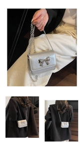 Detail of silver metallic mini bag with bow accent and chain strap worn by a model
