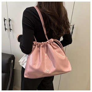 Dettaglio della borsa a spalla rosa lucida con coulisse e ornamento a fiocco argento