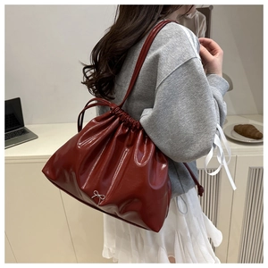 Dettaglio della borsa a spalla in pelle lucida rosso scuro con fiocco in metallo argento