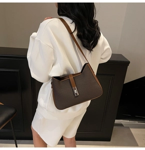 Rear view of a model wearing a brown woven texture shoulder bag with metal buckle detail