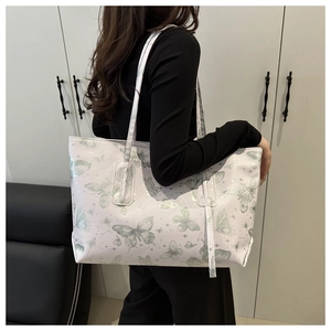 Detail view of large tote bag with butterfly prints and slim shoulder straps on model