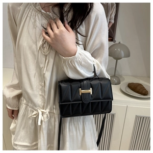 Nahaufnahme einer schwarzen gesteppten Tasche mit goldenem H-Verschluss am Model