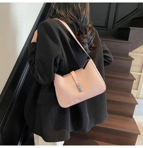Detail of pink textured underarm bag with silver metallic clasp on a black blazer