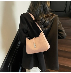 Detalle del bolso baguette rosa con textura diagonal y cierre giratorio plateado
