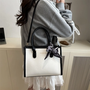 Elegante schwarz-weiße Handtasche mit Schlangenhautprägung, Rundgriff und Zierschal
