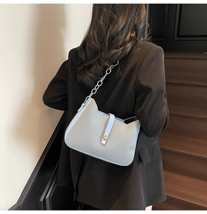 Detail showing grey woven fabric shoulder bag with light blue trim and silver chain strap