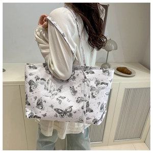 Macro shot of white tote bag featuring vintage butterfly and star prints on synthetic leather