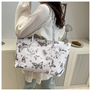 Detailed view of large tote bag with butterfly prints shown on model's shoulder