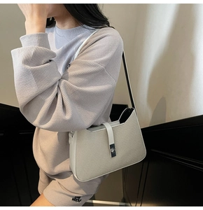 Detail of minimalist beige woven shoulder bag with white leather trim and silver clasp