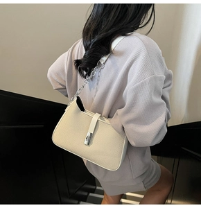 Detail of off-white woven texture shoulder bag with silver chain and twist lock clasp