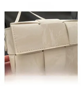 Detail of cream woven square handbag with marble textured leather and slim strap