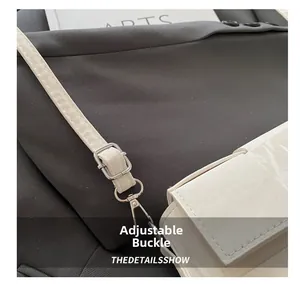 Detail of adjustable silver buckle and fine stitching on white woven shoulder bag
