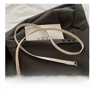 Detail of adjustable strap and silver metal buckle on a cream textured flap bag