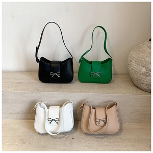 Four solid color underarm bags with metallic bow knots on tiered industrial display