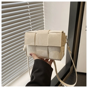 Detail of cream white woven crossbody bag showing textured synthetic leather and silver buckle