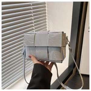 Detail of light blue woven leather crossbody bag showing intricate texture and silver buckle