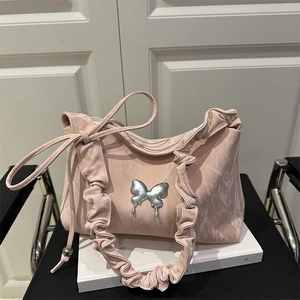 Sac plissé rose avec texture marbrée et boucle papillon argentée sur un livre blanc