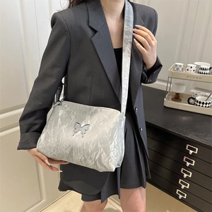 Borsa a spalla argentata plissettata con dettaglio a farfalla indossata con abito grigio