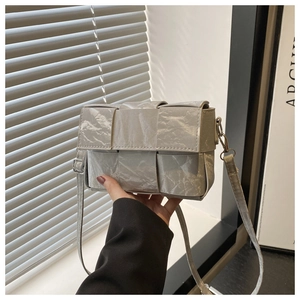 Close-up of silver-grey woven shoulder bag featuring premium metallic pleated texture