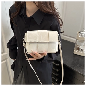 Detail shot of a white woven crossbody bag with marble texture finish worn by a model