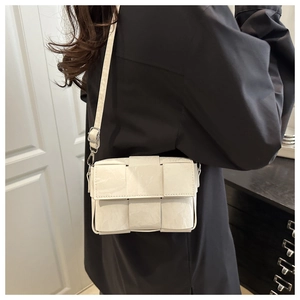 Detail of cream woven leather crossbody bag with adjustable silver buckle on model