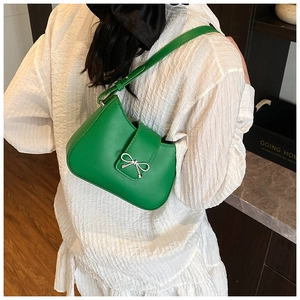 Detail of vibrant green underarm bag with silver bow buckle on white shirt