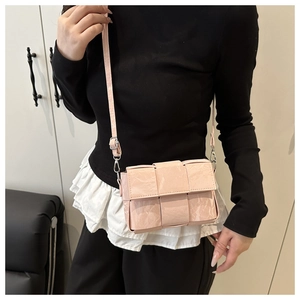 On-body view of pink woven leather crossbody bag with adjustable strap and silver buckle