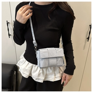 Detail of woven texture and adjustable shoulder strap on a light blue crossbody bag